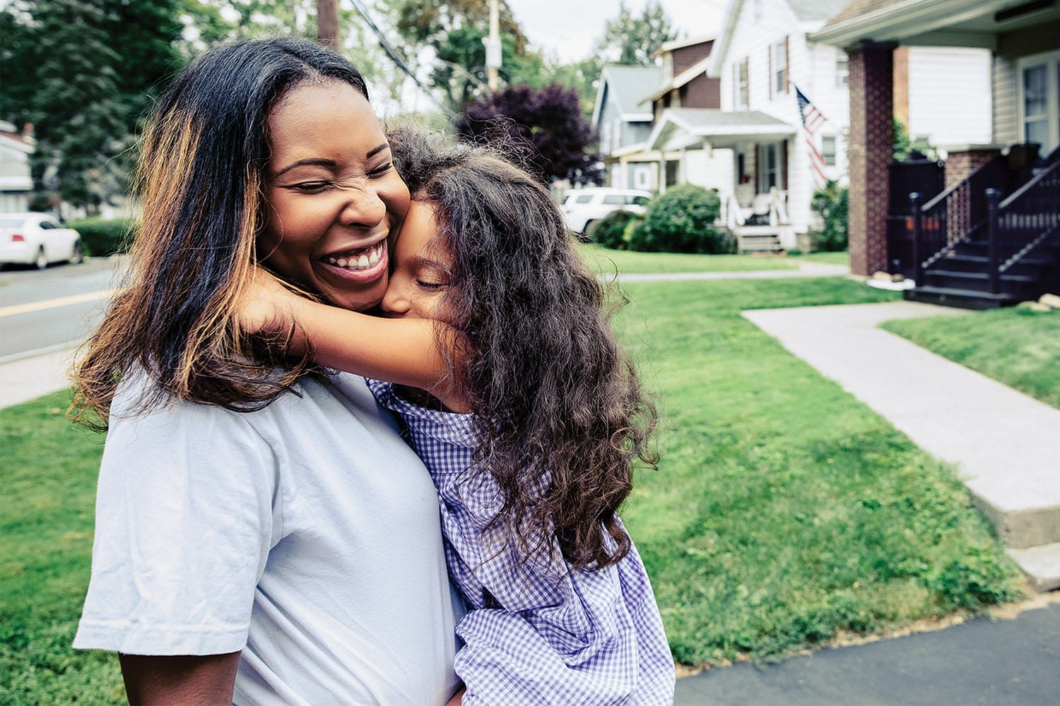 A mother and child hugging in front of a home